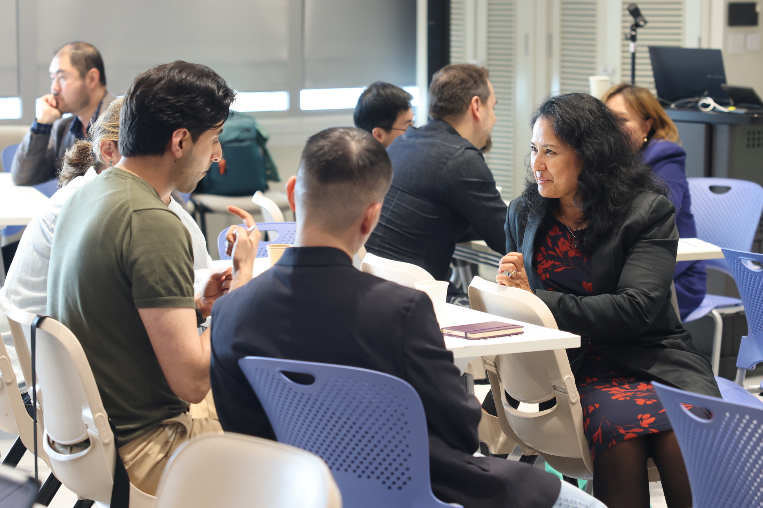 Small groups in conversation at tables during a CiC Symposium